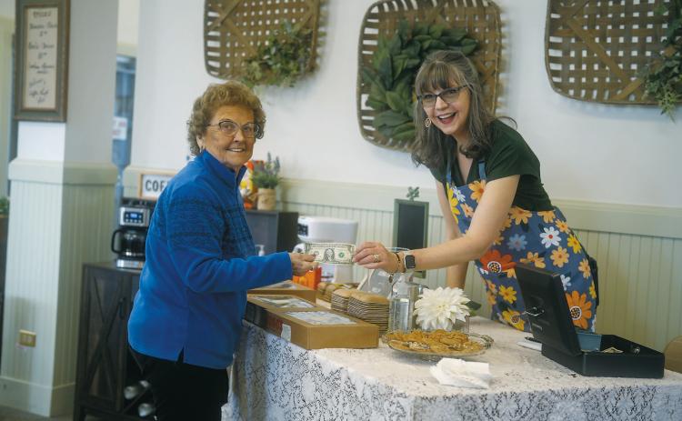 Mary Lou Swiscoski receives her first dollar bill from Gladys Kemnitz at the grand opening of Coffee, Thrift, and Gift. Photo by Jesus Ramos.