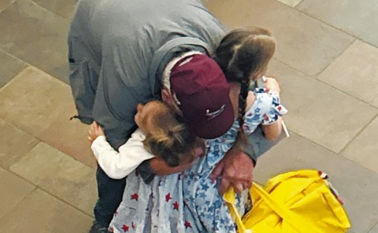 A veteran and grandfather greets his granddaughters after he arrived home from the Honor Flight. Photo by Rebecca Davis.