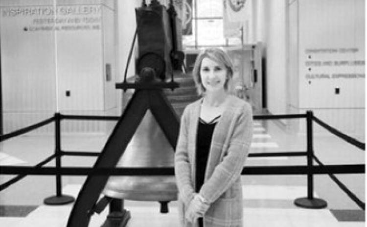 Melissa Klocke-Joyce, program coordinator for the ND250 Commission, stands next to a replica of the Liberty Bell at the North Dakota Heritage Center on Dec. 22, 2025. (Photo by Michael Achterling/North Dakota Monitor)