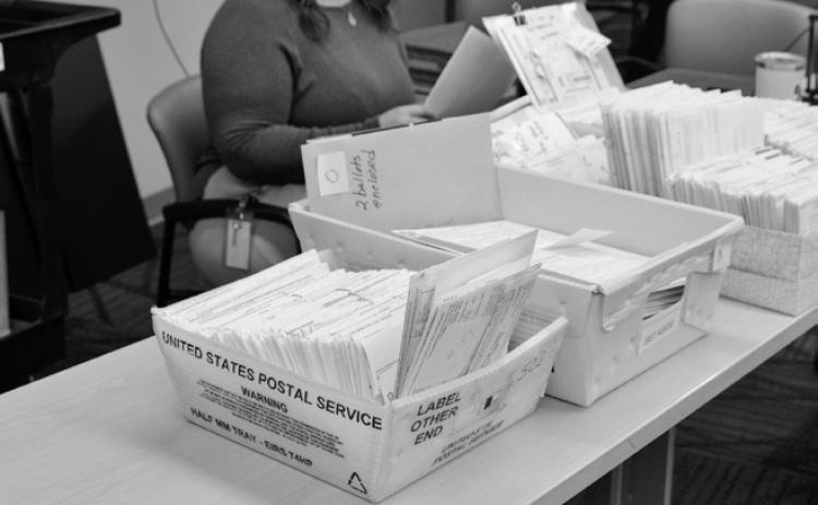 Ballots that had arrived by mail or were set aside on Election Day sit on a table at the Cass County Courthouse on Nov. 18, 2024, waiting to be reviewed. (Photo by Jeff Beach/ North Dakota Monitor)