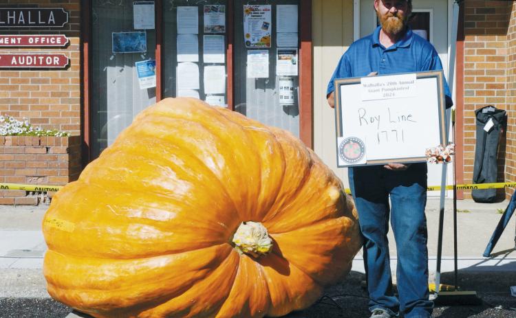 Roy Line stands with his record breaking giant pumpkin. Photo by Larry Stokke.