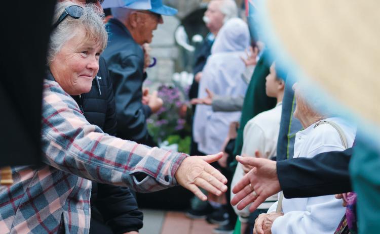 Canadians and Americans reach across the border to shake hands in an event celebrating friendship between the two nations at the International Peace Garden on Aug. 9, 2025. (Photo by Mary Steurer/North Dakota Monitor)