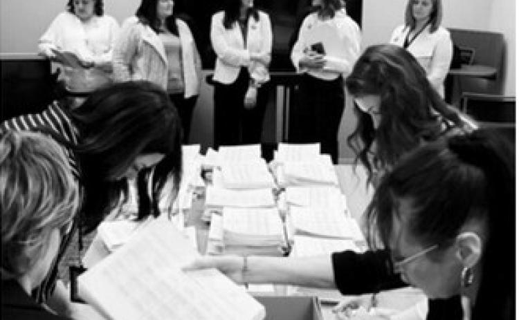 Members of the sponsoring committee for a proposed ballot measure to make public school meals free watch as staff with the North Dakota Secretary of State’s Office count petition signatures on April 9, 2026. (Photo by Mary Steurer/North Dakota Monitor)