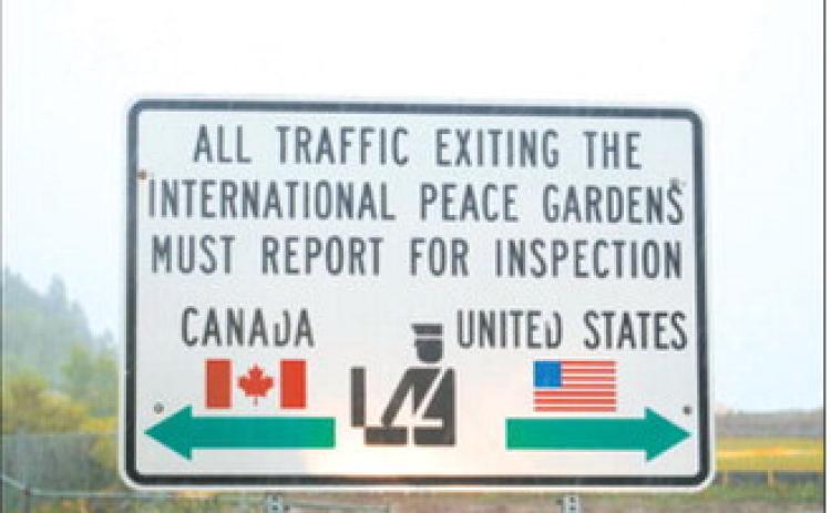 A sign marking the U.S.-Canada border is pictured on a rainy day near Dunseith, North Dakota. (Photo by Mary Steurer/North Dakota Monitor)