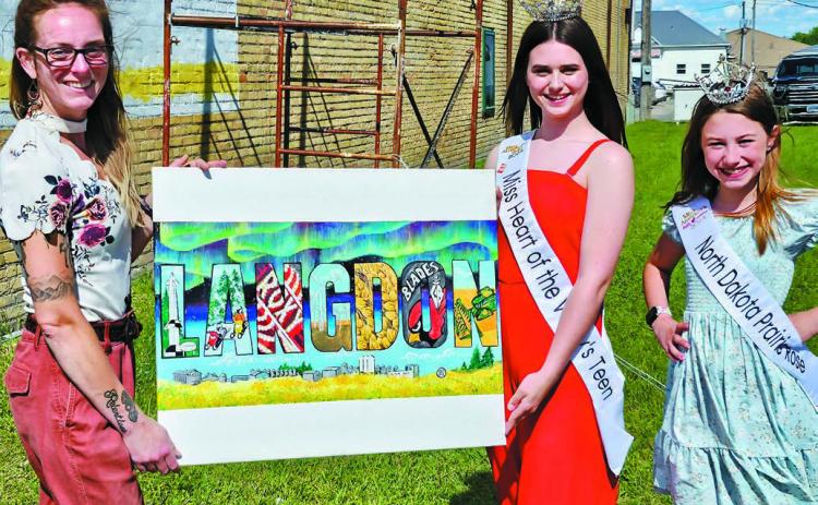 A large canvas displays what the Langdon mural will look like upon completion and was debuted recently for a dedication ceremony in which Miss Heart of the Valley’s Teen and North Dakota Prairie Rose attended. Photo by Nick Vorlage.