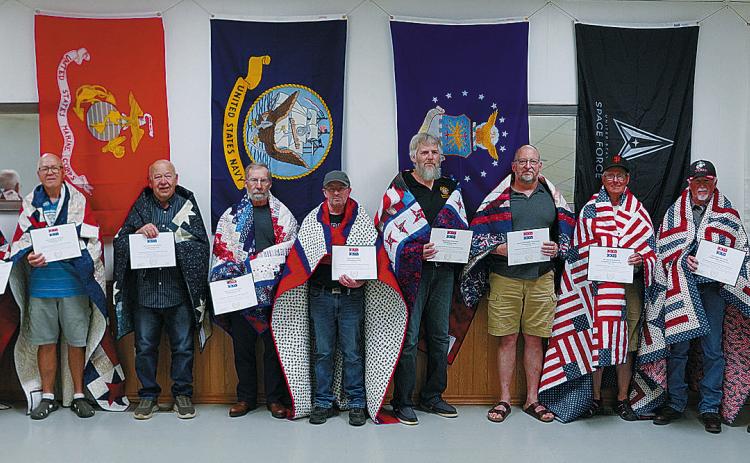 The Quilts of Valor recipients (L-R): Grant Nelson, Arnold Jordan, Harvey Metzger, Wayne Magnus, Lyle Long, Tony Phillips, Jerry Nowatzki, Tom Perius, Terry Metzger, and Kenny Girodat. Photo by Larry Stokke.