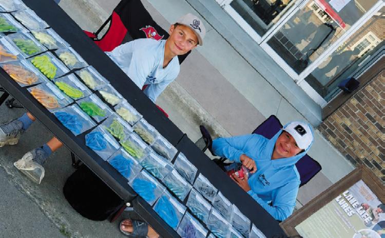 Prestyn Bodnar, left, and Kyler Farris display their handmade fishing lures from Lake Life Lures at a summer market. Photo courtesy of Brittany Farris